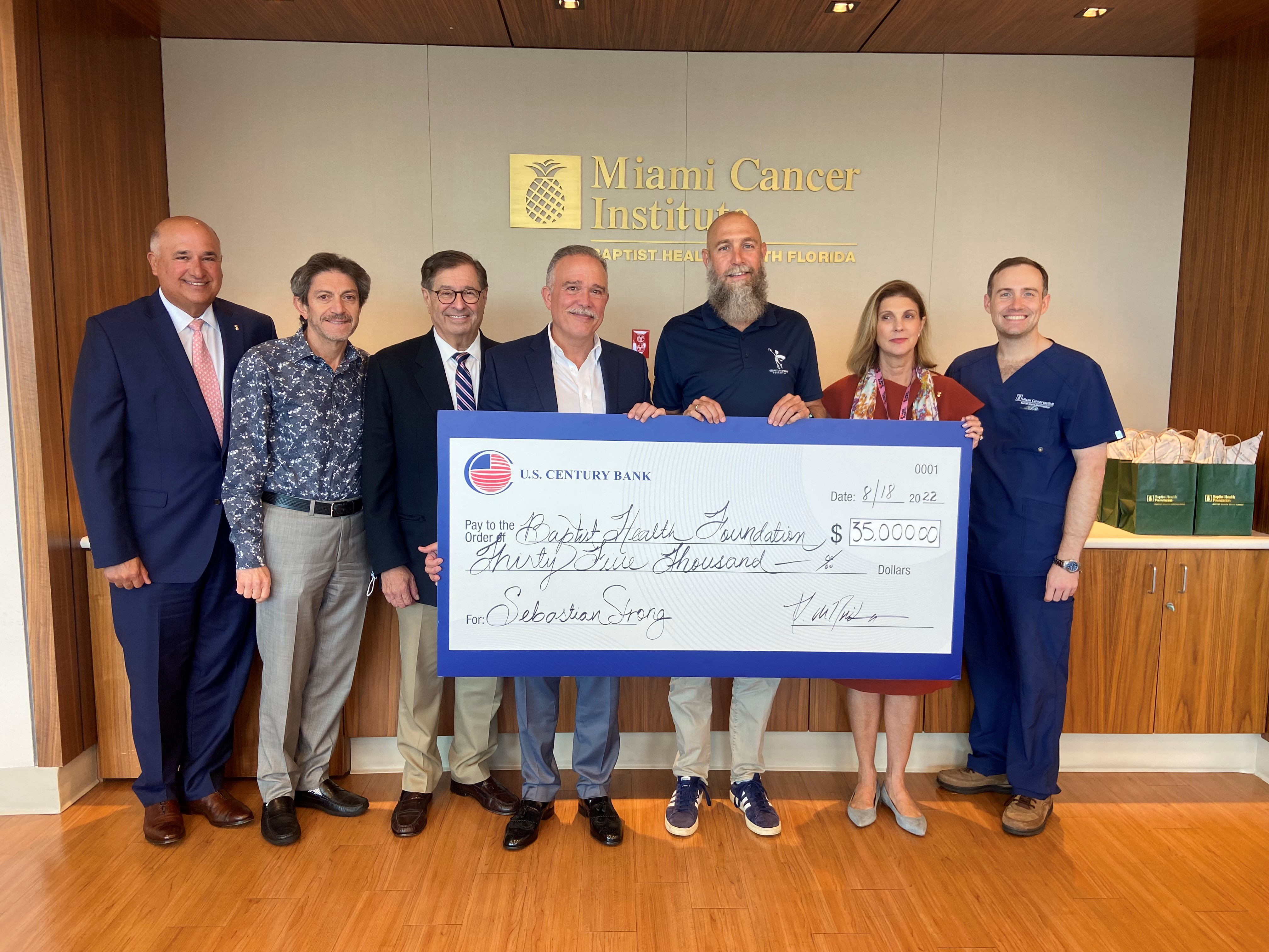 Group of men and woman holding a donation check at the cancer institute