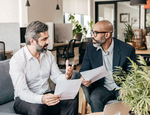 two men dressed in business attire discussing work plans