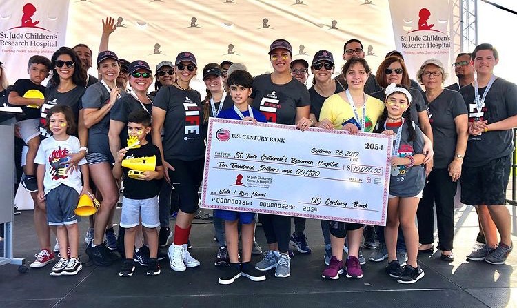 U.S. Century Bank employees holding a donation check